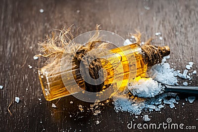 Close up of aurvedic herb camphor powder in a small spoon and its oil on brown wooden surface in dark Gothic colors is helps in Stock Photo