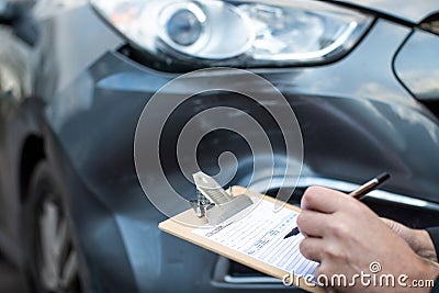 Close Up Of Auto Workshop Mechanic Inspecting Damage To Car And Filling In Repair Estimate Stock Photo