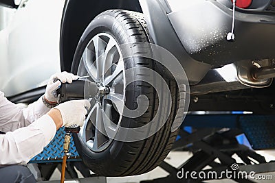 Automechanic with electric screwdriver changing tire in garage Stock Photo