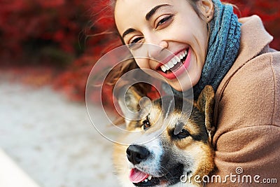 Close-up autumn portrait happy woman and pet Welsh Corgi dog with funny face on red fall leaves background. Stock Photo