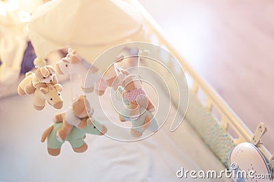 Close-up baby crib with musical animal mobile at nursery room. Hanged developing toy with plush fluffy animals. Happy parenting an Stock Photo