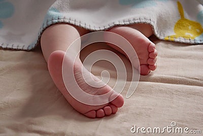 Close up of baby feet peeking out of blanket. The child is sleeping Stock Photo