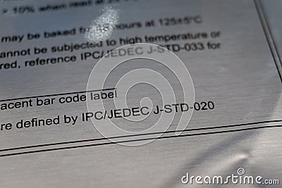Close-up of bag caution warning label IPC JEDEC J-STD-020 standard reference from electronics manufacturing industry Editorial Stock Photo