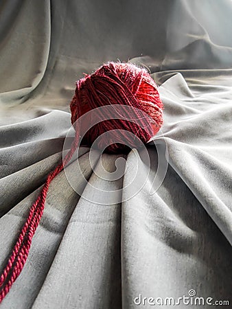 Wool red ball with grey fabric underneath Stock Photo