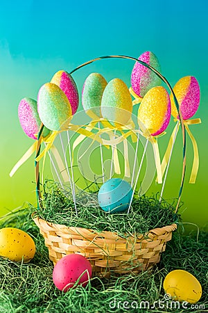 A close up of a basket of colourful Easter eggs decorated with sparkles sitting on grass. Stock Photo