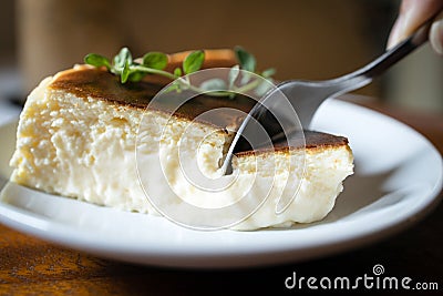 Close Up,Basque Burnt Cheesecake,Tarta de Queso or San Sebastian Cheesecake on a white plate with a spoon to scoop the soft cheese Stock Photo