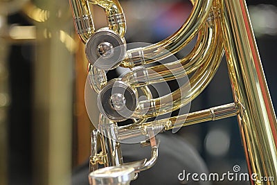 Close-up of a bass trombone tube with a fourth and fifth valve. Whorls in golden brass metal. Jazz trombones detail view with Stock Photo