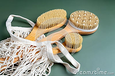 Close up of a bath bamboo brushes for dry massage in cotton mwsh bag on green background. Home spa and relaxation tools. Stock Photo