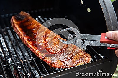 Close-up Of BBQ Roast and Smoked Pork Spareribs glazed with sauze On The Hot Charcoal Grill With Flames, Barbecue and Stock Photo