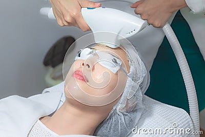 Close up of beautician hand making ultrasound facial procedure by special equipment Stock Photo