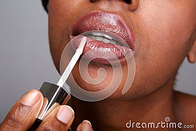 Close up beautiful african american woman applying shiny lip gloss Stock Photo