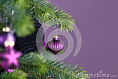 Close up of beautiful purple riffled glass tree bauble on decorated Christmas tree with other seasonal tree ornaments Stock Photo