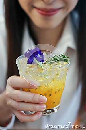 Close up a beautiful woman with Passion fruit juice iced in a glass on wooden table in cafe Stock Photo