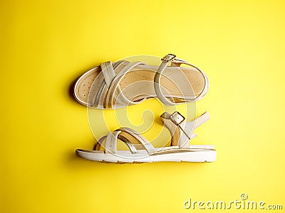 Close up of beige leather summer comfortable women`s sandals on brigth yellow background. Top view, side view, flat lay Stock Photo