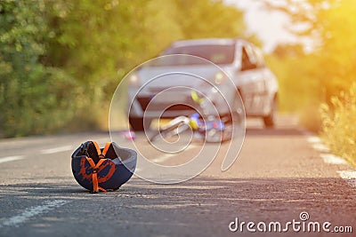 Close-up of a bicycling helmet fallen on the asphalt next to a b Stock Photo