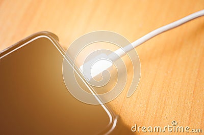 Black color mobile smart phone charging on wooden table. Stock Photo