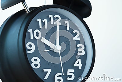 Close up of black color vintage alarm clock on white wall, time Stock Photo