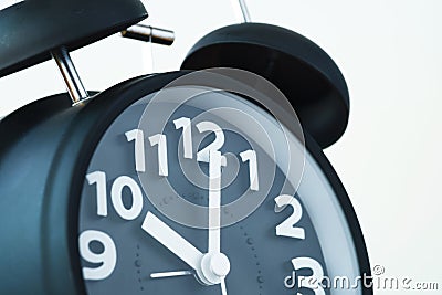 Close up of black color vintage alarm clock on white wall, time Stock Photo