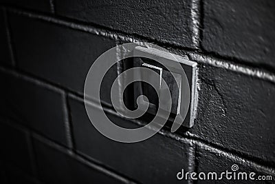 Close-up of black electric switch button on brick textured wall. Stock Photo