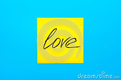 Close up black handwritten inscription love on one yellow square sticker on blue background with copy spase Stock Photo