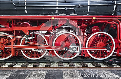 Close-up of black heritage steam train on railway tracks with red wheels and transmission engine Stock Photo