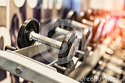 Close up of black metallic steel dumbbell set. Dumbbells on rack in sport fitness center. Workout training and fitness gym concept Stock Photo