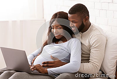 Close up of black pregnant couple using laptop at home Stock Photo