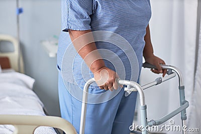 Close up of black senior woman leaning on walker support in hospital room Stock Photo