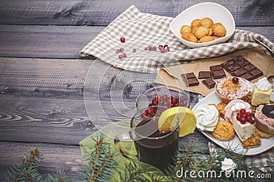 Close-up of blue spruce twigs, gingerbread cookies, cinnamon sticks, slices of dried orange and white meringues, a glass of tea Stock Photo