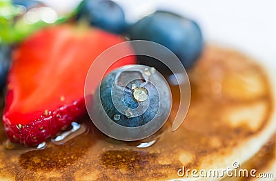 Close up of a blueberry with a drop of honey on the stack of pancakes. Stock Photo