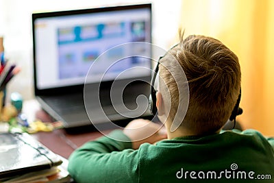 Selektive focus image.The boy learns with laptop at a distance remote learning,boy uses headphones with a microphone Stock Photo