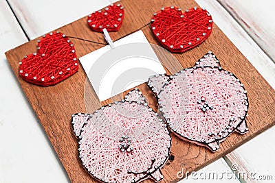 Close - up of the Board with nails wound with threads in the form of hearts and pigs and a piece of paper on a thread Stock Photo
