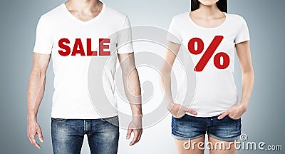 Close up of the bodies of man and woman in a white t-shirts with the red percentage sign and the word ' sale ' on the chest. Stock Photo