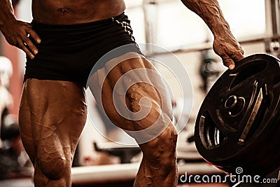 Close-up of bodybuilders muscular legs. Athlete man doing workout exercise in gym. Stock Photo