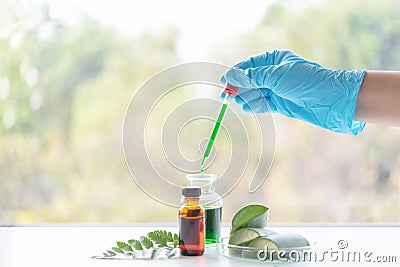 Close up bottle of essential oils with scientist holding dropper. Lab research for scent extract for the new skincare product Stock Photo