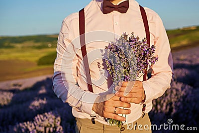 Close-up of a bouquet of lavender in the hands of the groom. Stock Photo