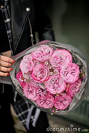 Close up of a bouquet of pink roses with tiny daisies, wrapped in gray wrapping paper Stock Photo