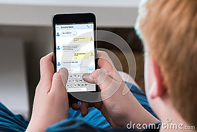 Boy Typing Text Message On Mobile Phone Stock Photo