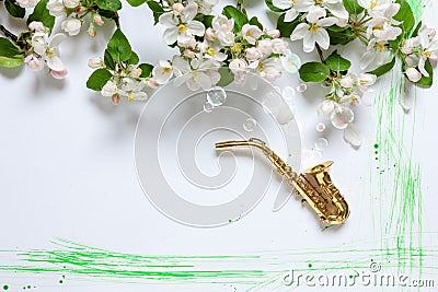 Close up of Branch of blossoming apple tree and miniature tiny golden saxophone on white background with brush strokes made in Stock Photo