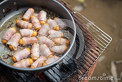 Close up,Breakfast for all ages,Pigs in Blankets or Mini sausages wrapped in smoked bacon on a hot frying pan on a charcoal grill Stock Photo