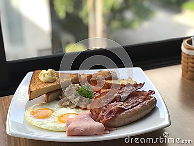 close up breakfast plate include fried eggs, ham, sausages, potatoes, tomatoes, mushrooms, beans Stock Photo