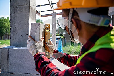 Close-up bricklayer builder using the water level, check the inclination of autoclaved aerated concrete blocks. Walling, Stock Photo