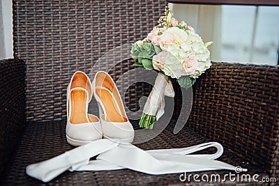 Close-up of bridal bouquet of roses, wedding flowers for the ceremony on the bed in a hotel room with white shoes Stock Photo