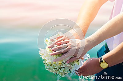 Close-up Bride and groom`s hands with wedding rings and bouquet. Love and marriage. Wedding accessories and decor on the backgrou Stock Photo