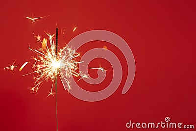 Close up of Brightly burning sparkler on a red background with lots of sparks Stock Photo