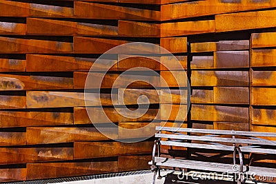 Close-up of brown metal tiled wall with empty bench. Rustic rectangular pieces creating pattern Stock Photo