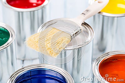 Close-up brush lying on multicolored paint cans Stock Photo