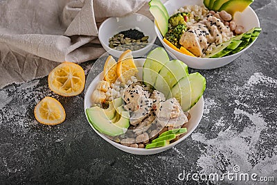 Close up Buddha bowl with chicken meat, bulgur, white beans, quinoa, avocado, lemon and fresh cucumber Stock Photo