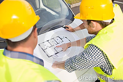 Close up of builders with blueprint on car hood Stock Photo