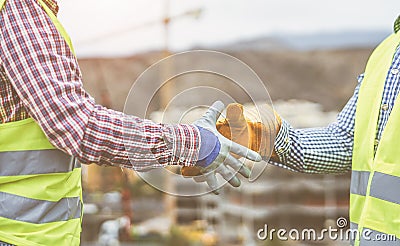 Close up builders hands making a deal - Workers on construction site reaching an agreement Stock Photo